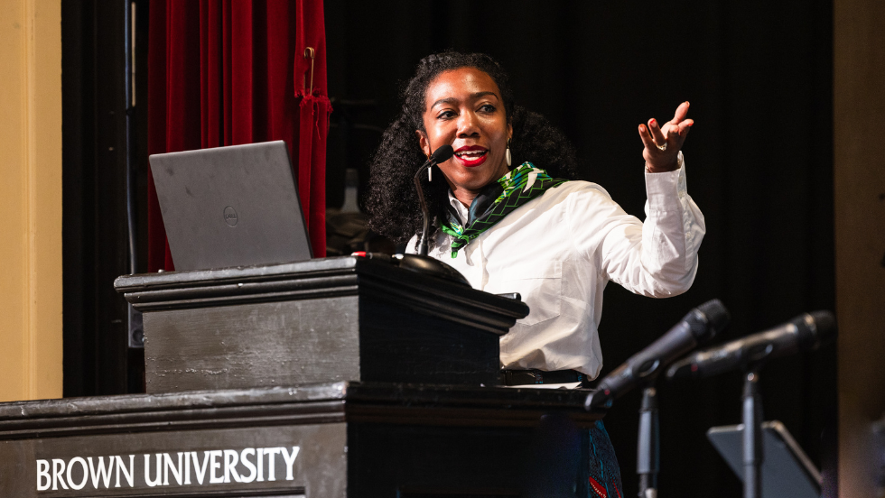 A speaker stands at the podium and gestures to the side.