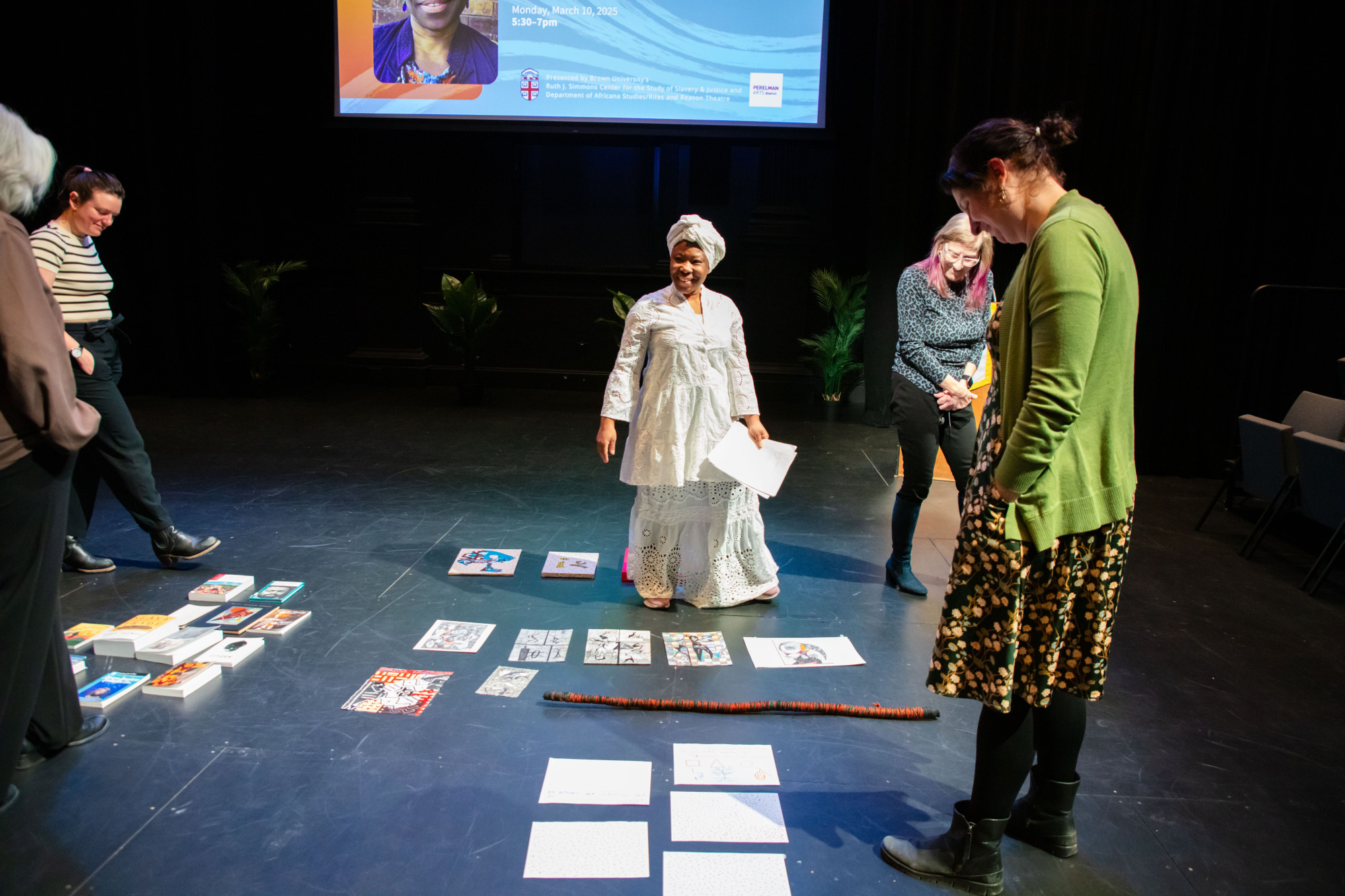 Woman placing papers on the ground as others circle them.