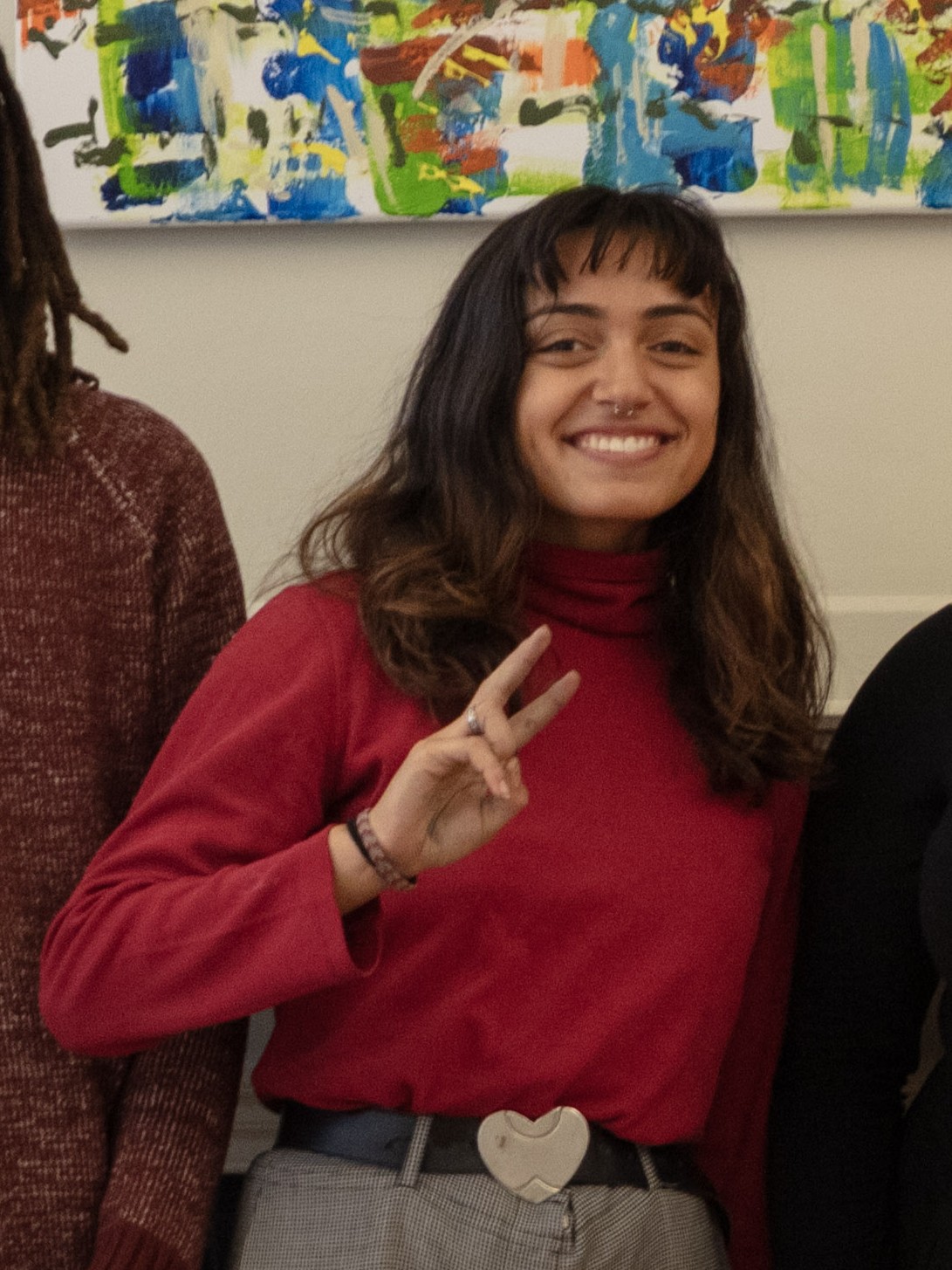 Woman wearing red top and putting up peace sign.