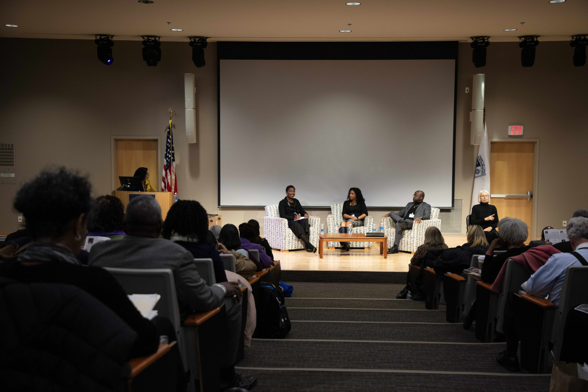 A panel of people sitting in front of an auditorium of people.