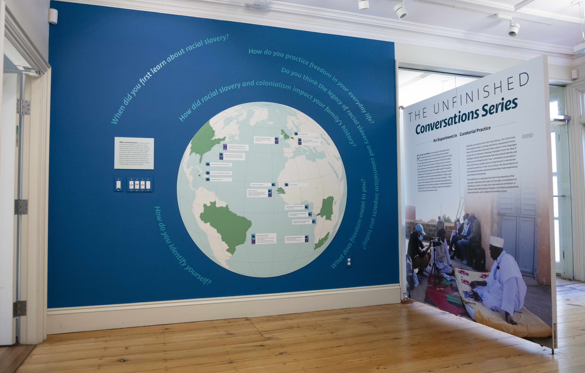 A wall with a bisecting panel featuring a graphic of a globe and pictures of people for an exhibition