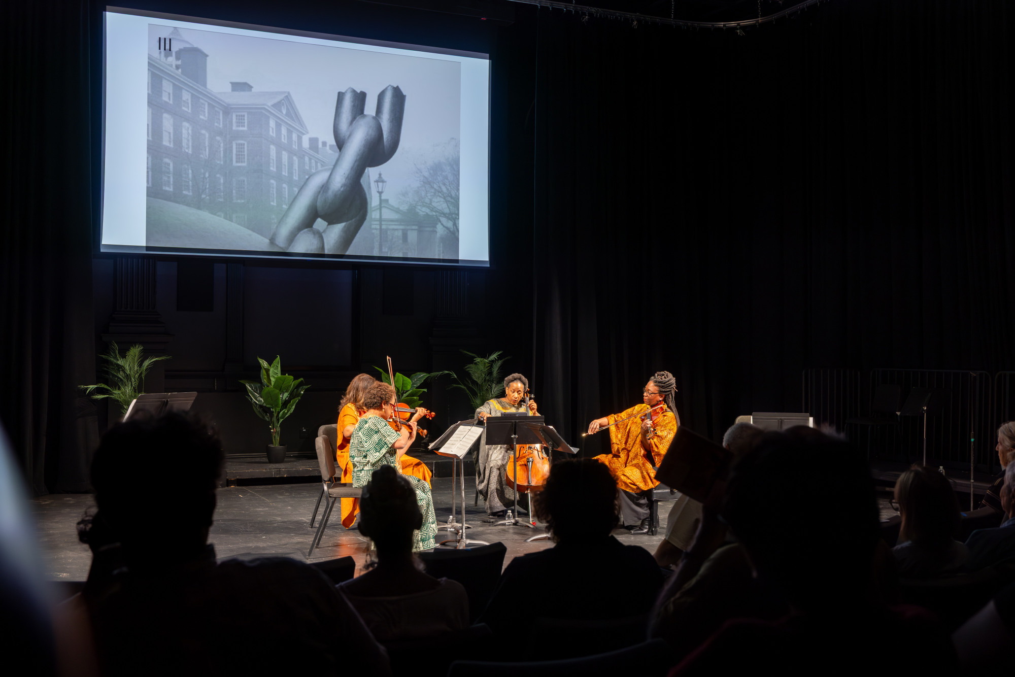 A string quartet performing on a stage in front of an audience.