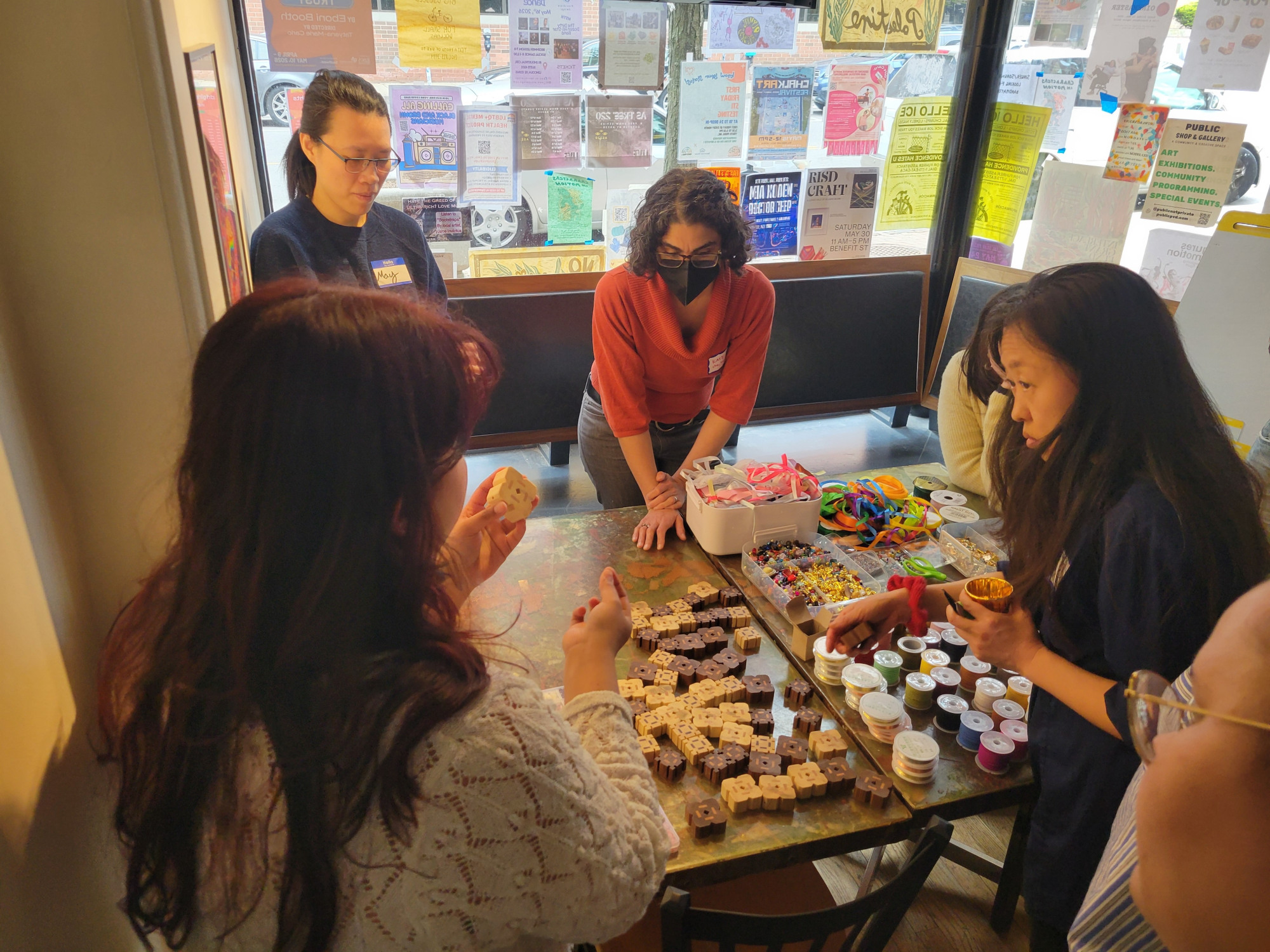 A group of people standing around a table full of different colorful items.