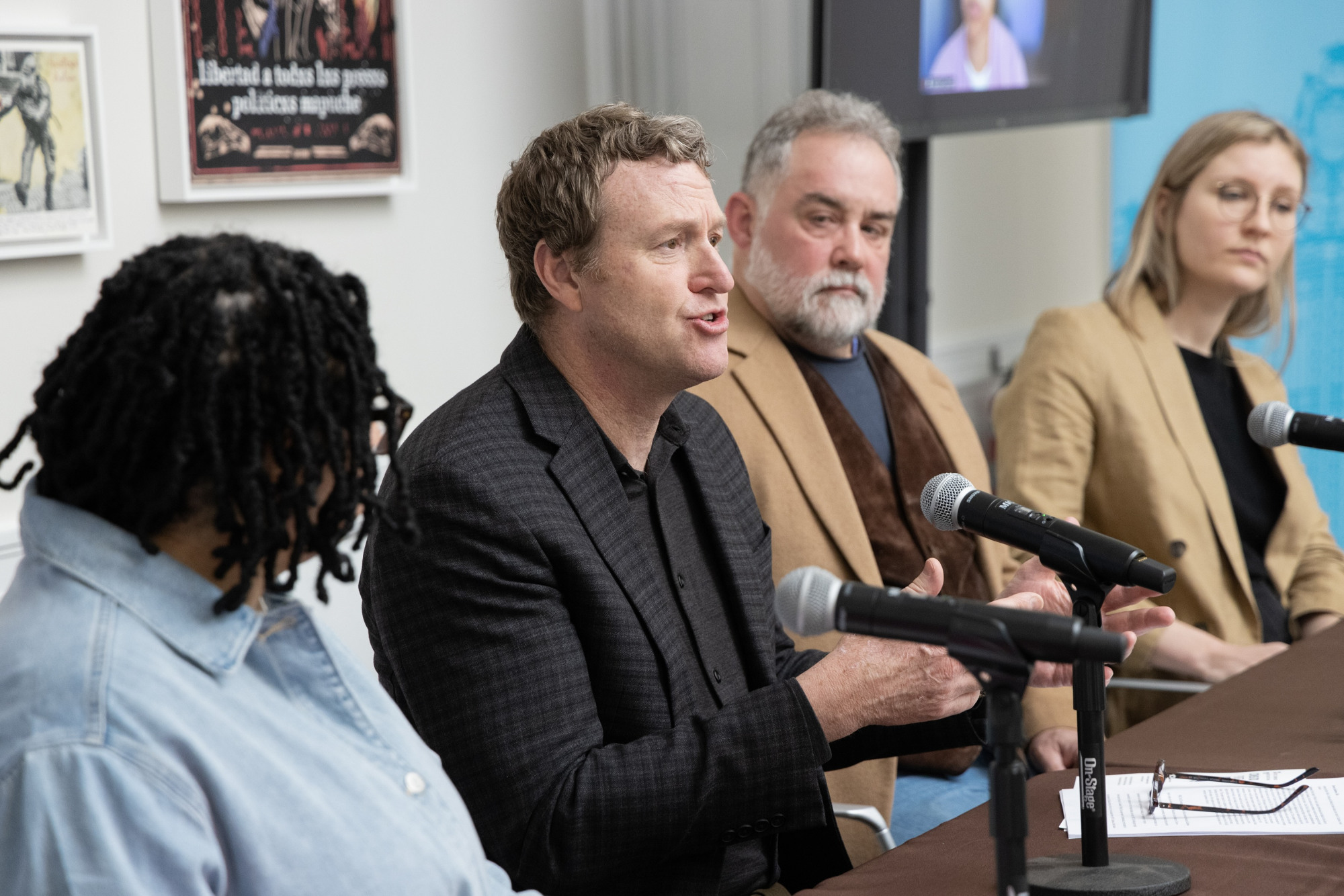 A group of people sat behind a table with mics.