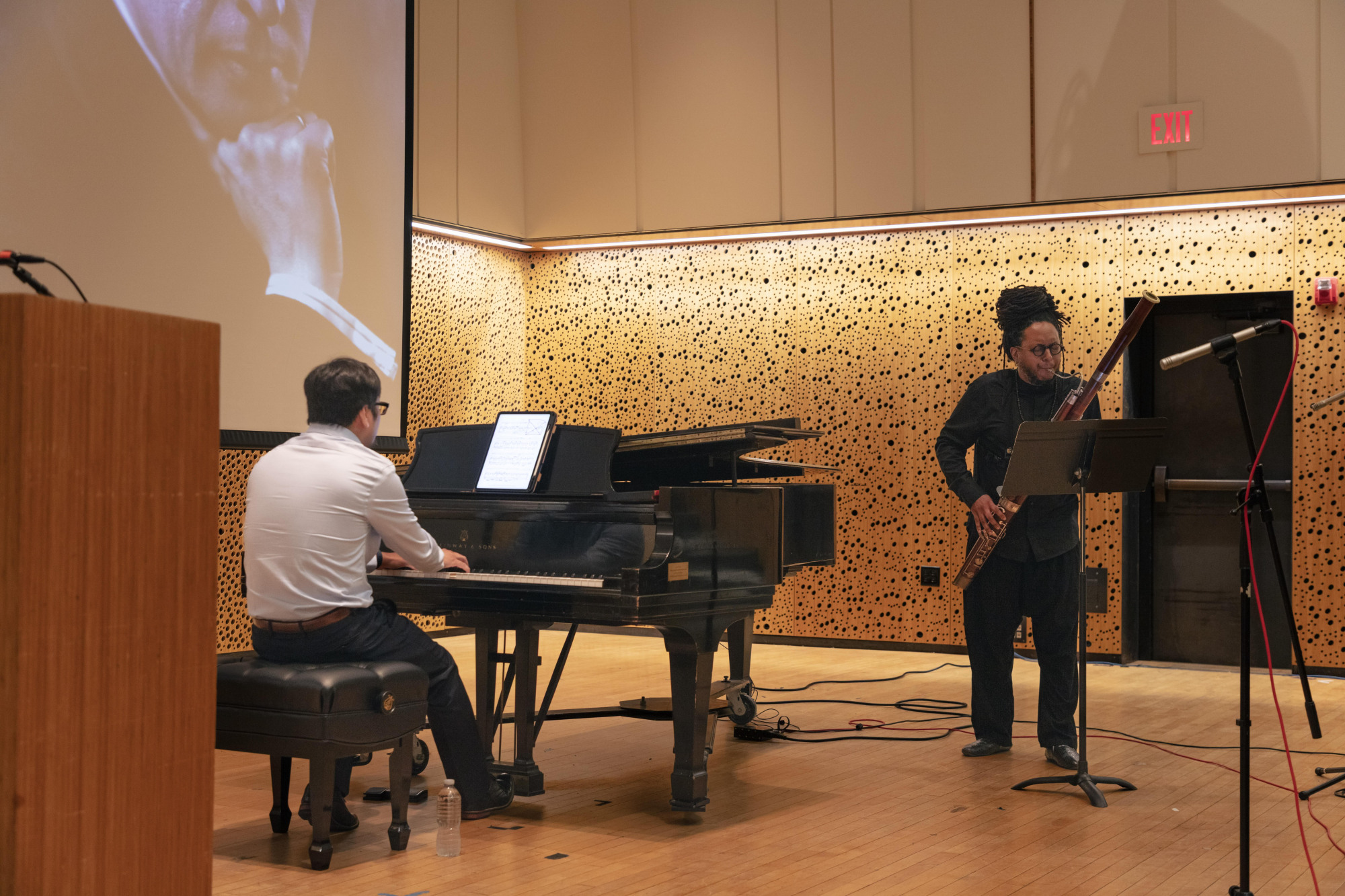 A man playing a grand piano and a man playing a bassoon.