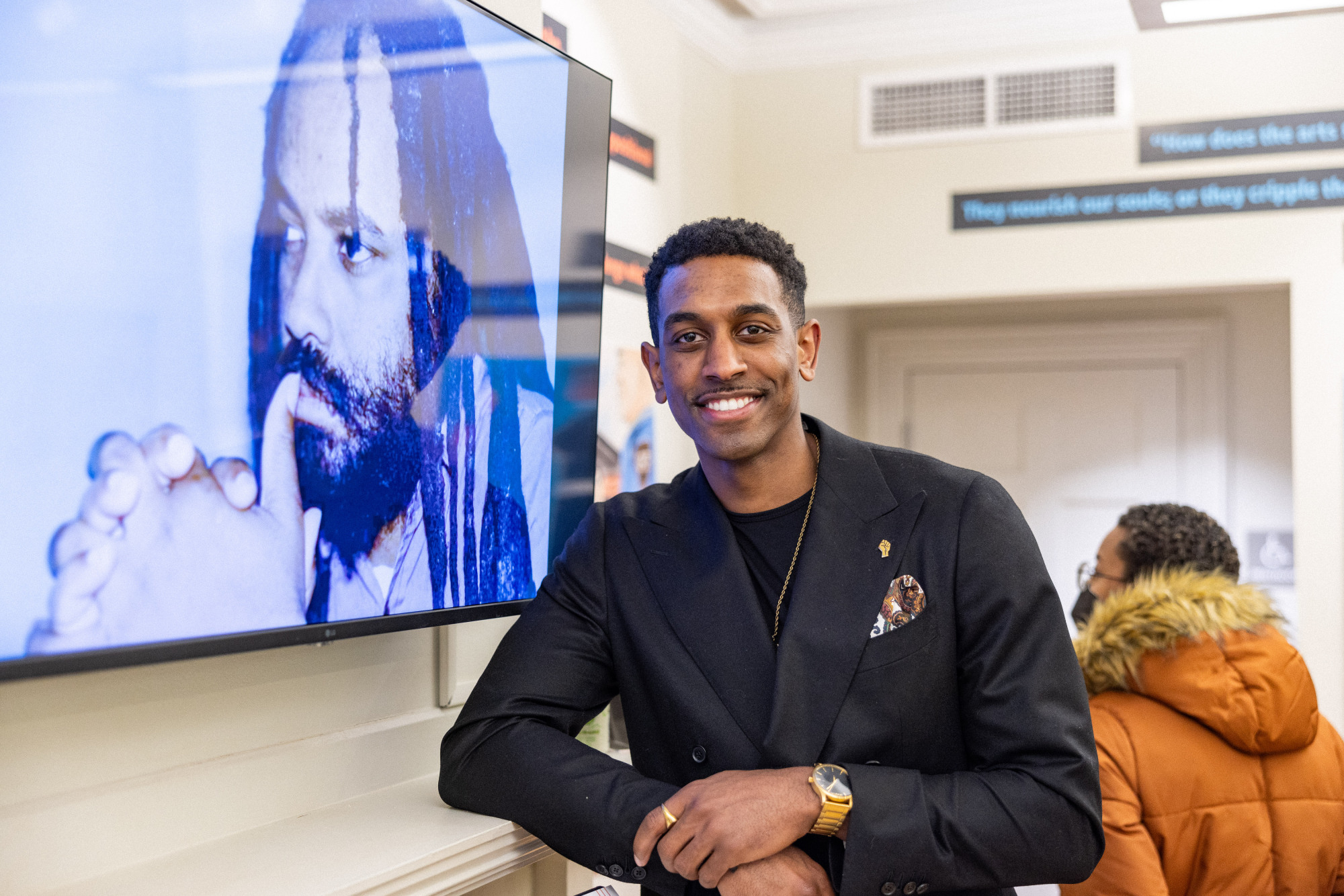 Man standing in front of TV screen smiling