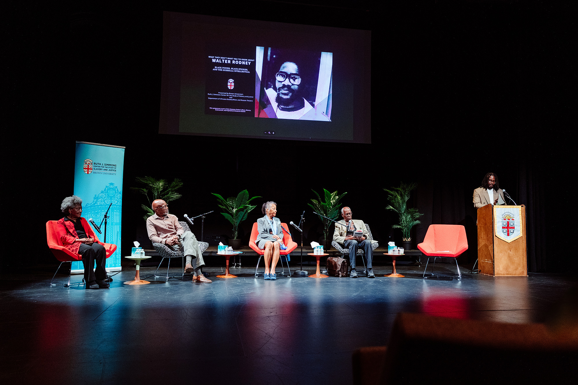 Five people on stage at a symposium