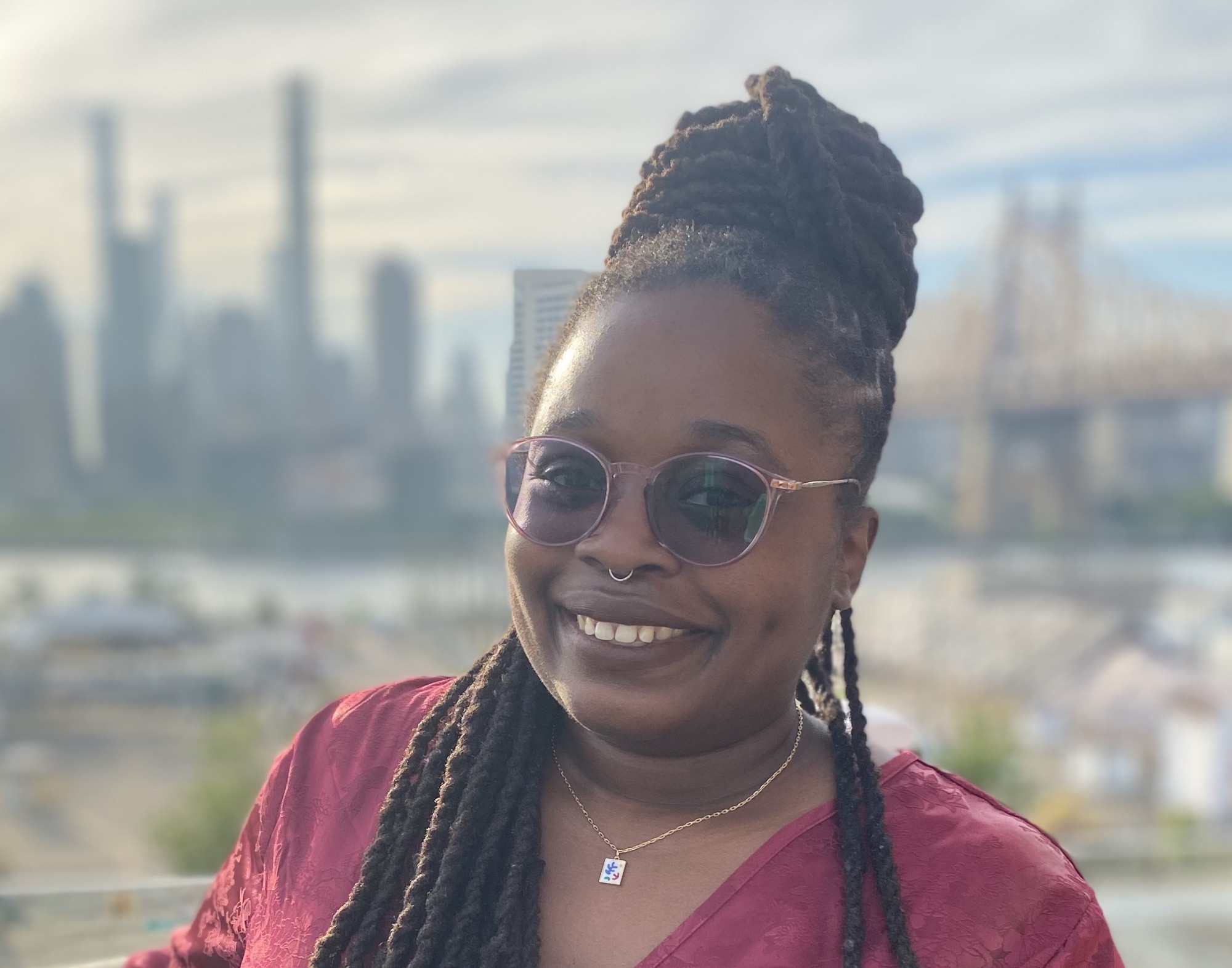 Alycia Hall poses in sunglasses and a red blouse for a headshot.
