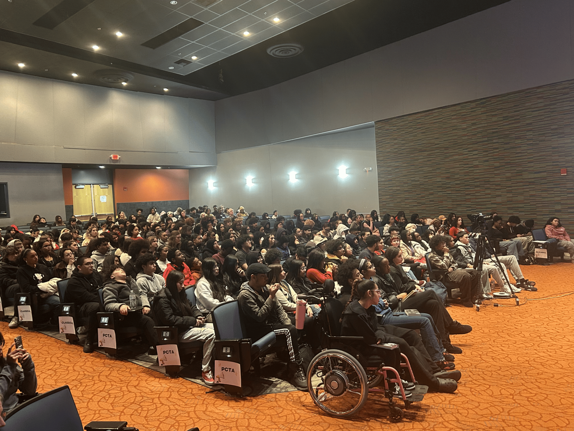 Auditorium full of people sitting.