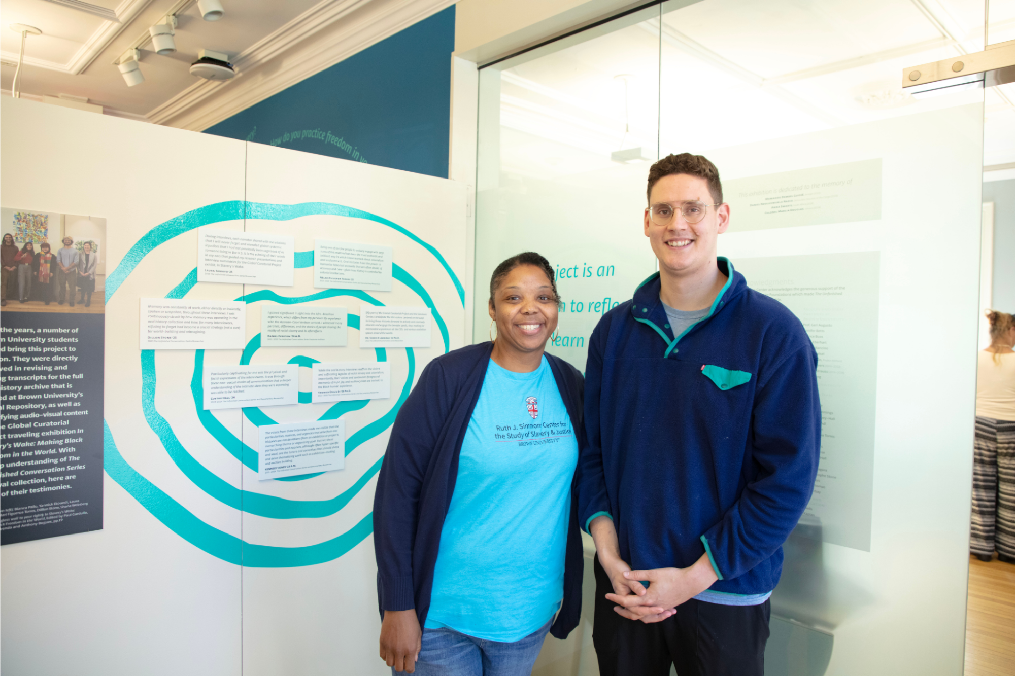 Two people smiling and standing in front of an exhibition