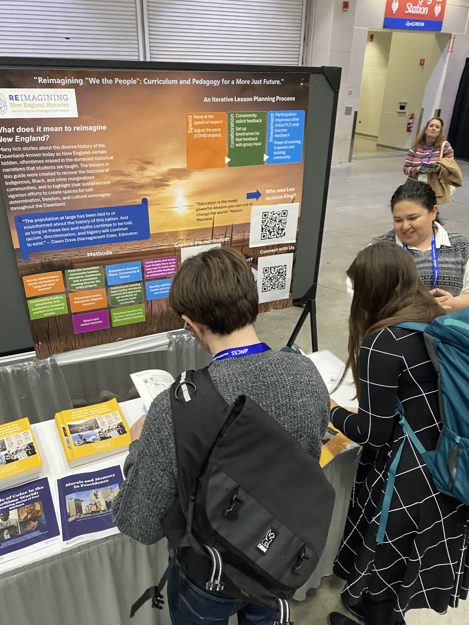 Group of people standing around a presentation.