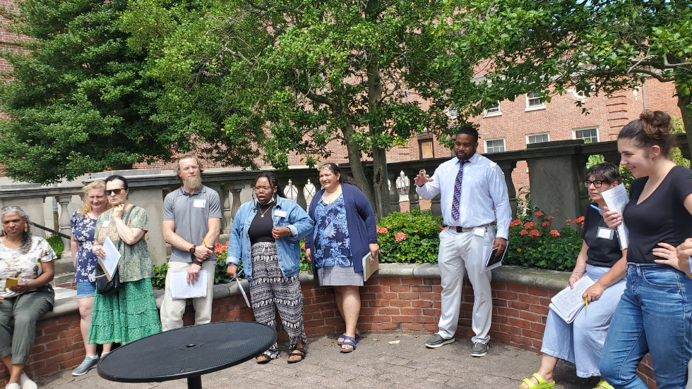 Dr. Mack Scott speaks to a group of nine educators in a patio at Brown University.