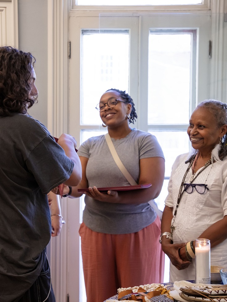 Two people face the camera smiling as a young person accepts a certificate and looks at the community altar