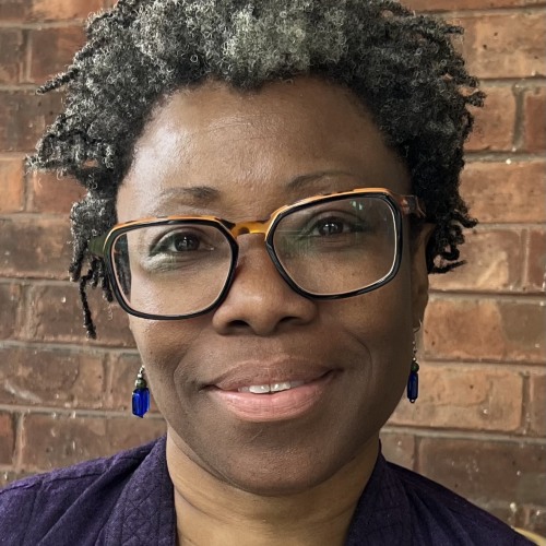 A woman smiling at the camera and wearing glasses