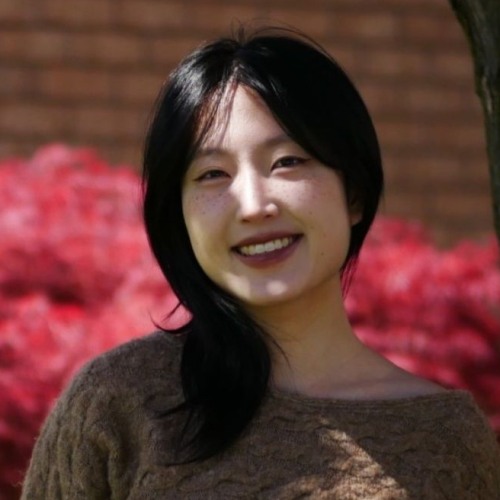 A woman standing outside smiles at the camera