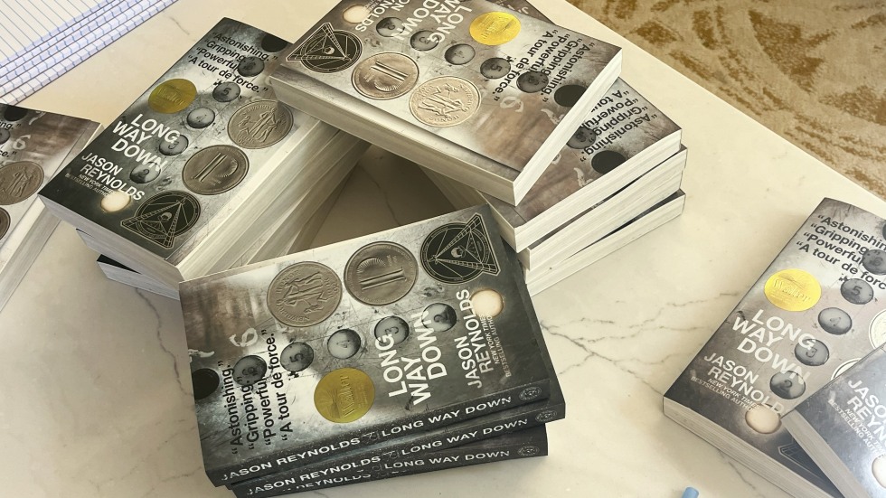 A Table with several copies of Jason Reynolds' book "Long Way Down and For Everyone"