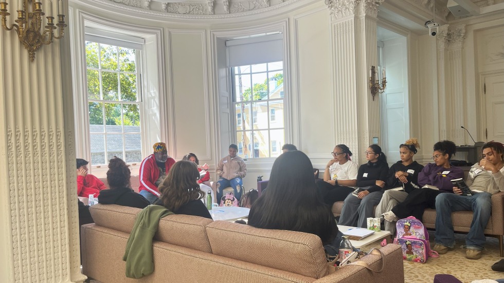 Students sit in plush couches while listening to their teacher