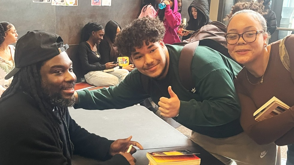 Jason Reynolds poses with two smiling high school students