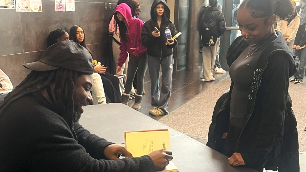 Jason Reynolds signs his book for a student