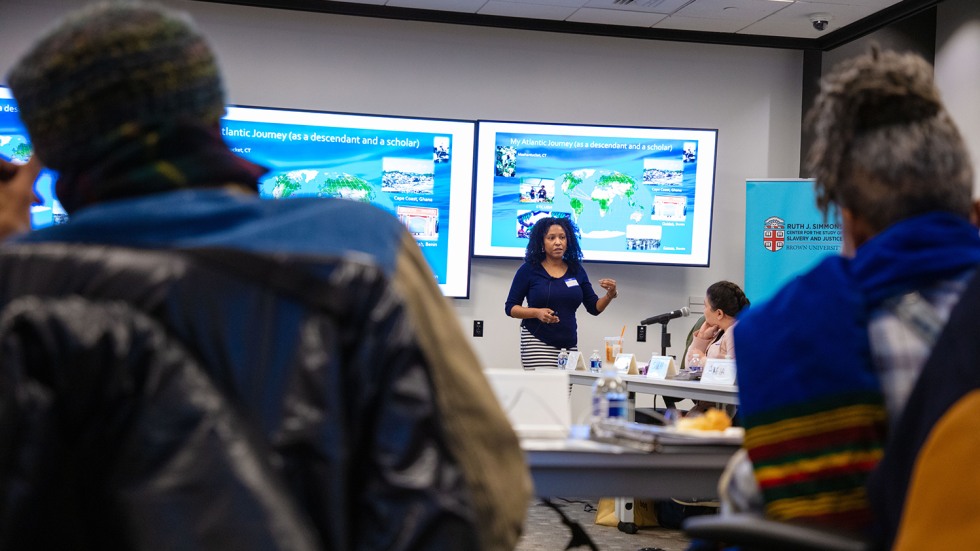 Akeia de Barros Gomes, stands in front of a presentation screen while speaking with educators
