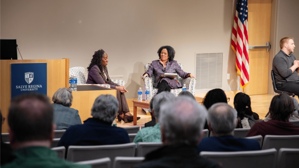 two panelists sit on the stage and engage in dialogue