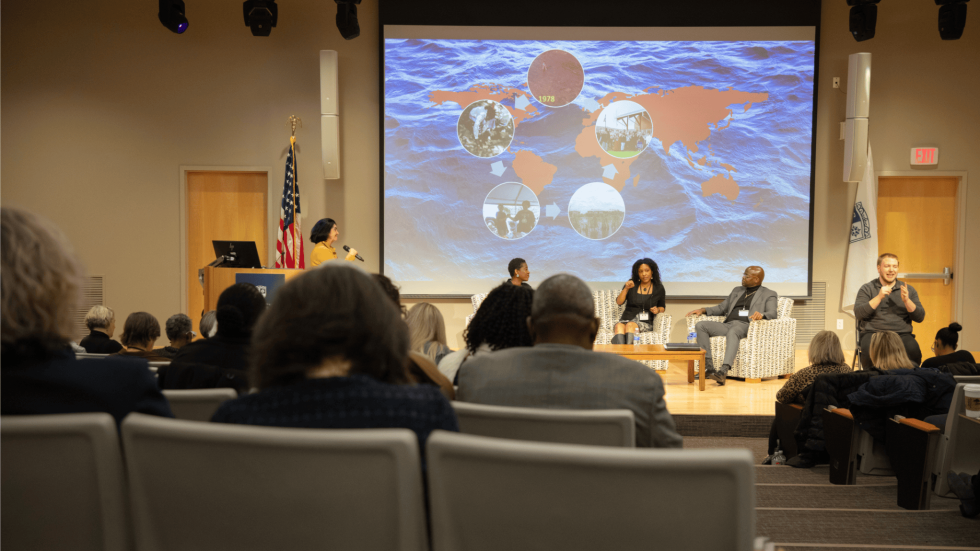 Three panelists sit at the front of a room.