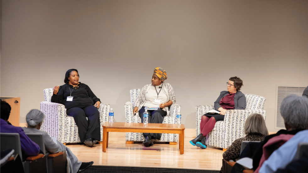 Three panelists converse around a table