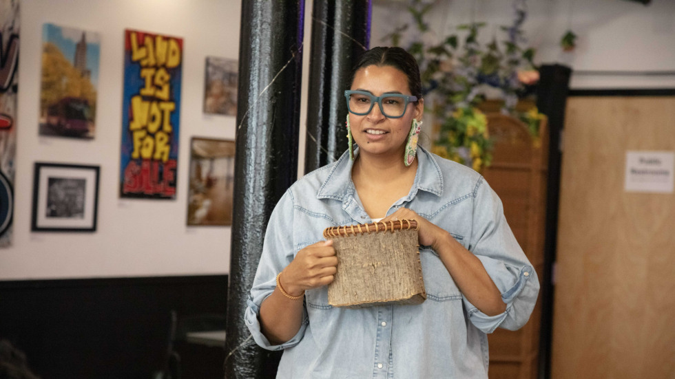 Woman standing and holding a bark basket in her hands
