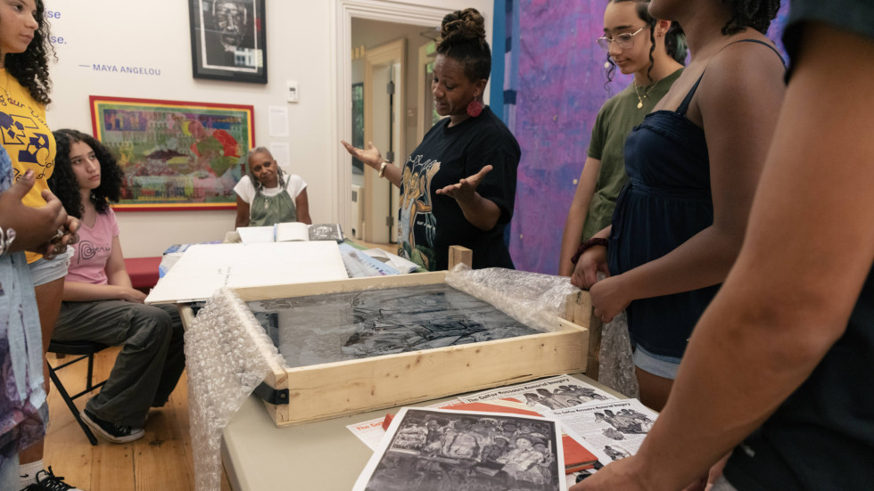 Group of people standing around a table of artwork.
