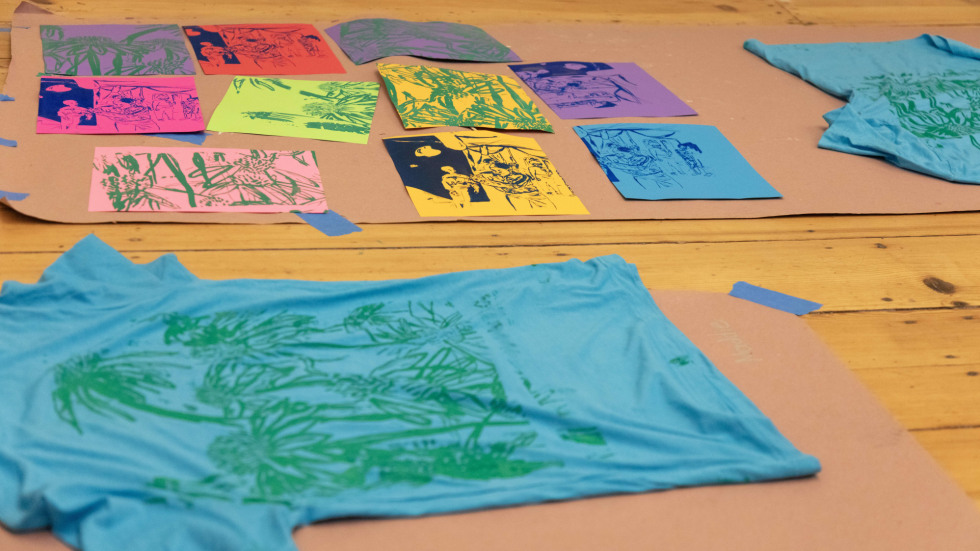 Colorful tshirts and pieces of paper laid out on the floor.
