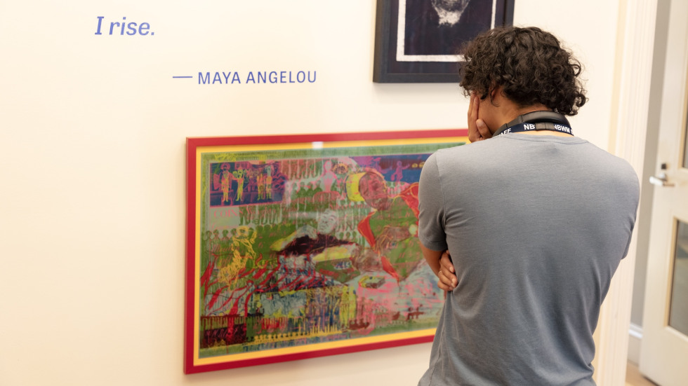 Visitor looking at a colorful print on a gallery wall while holding his head.